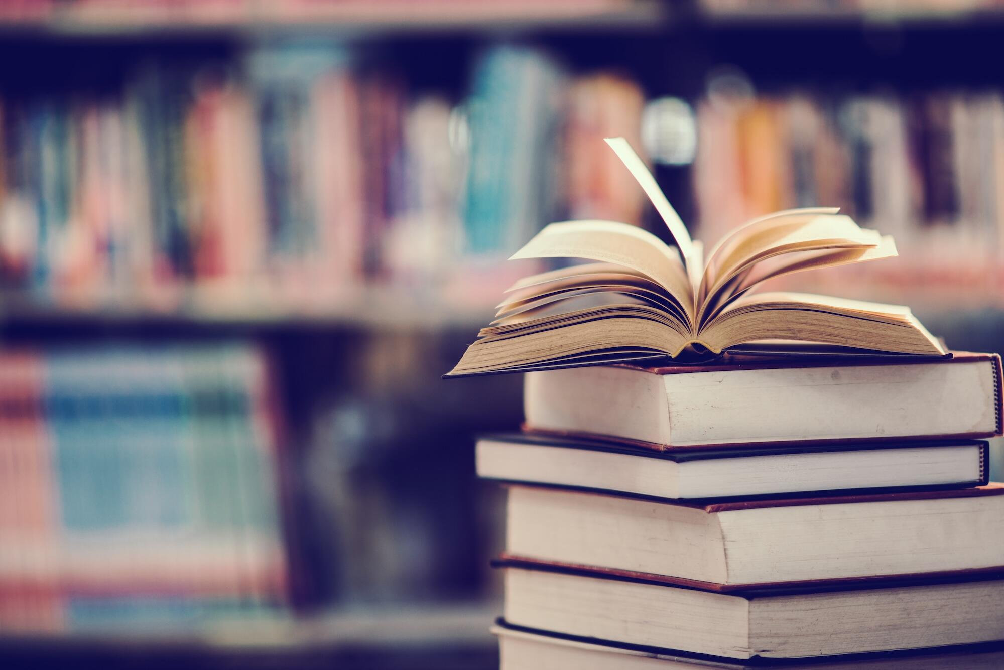 Des livres sont empil&eacute;s avec un livre ouvert sur le dessus